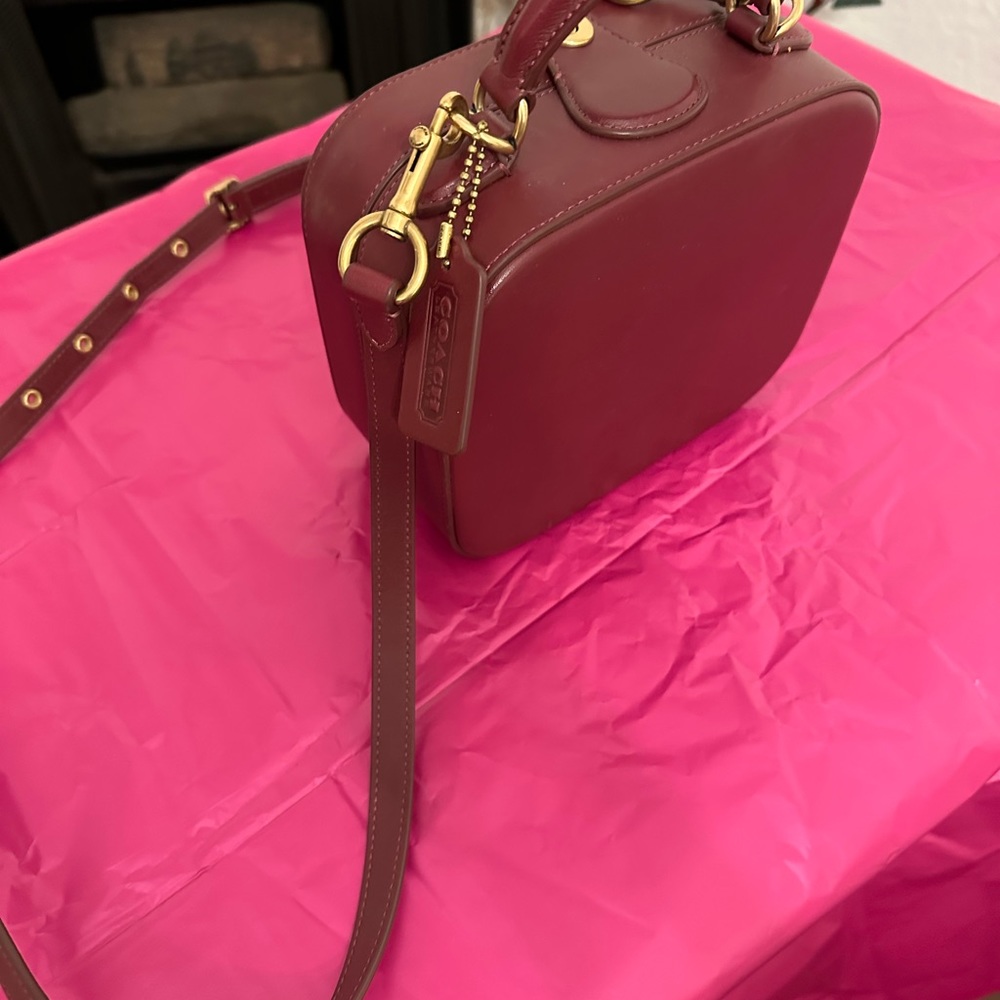 Burgundy Coach crossbody bag. Button open. Long shoulder strap. Leather.